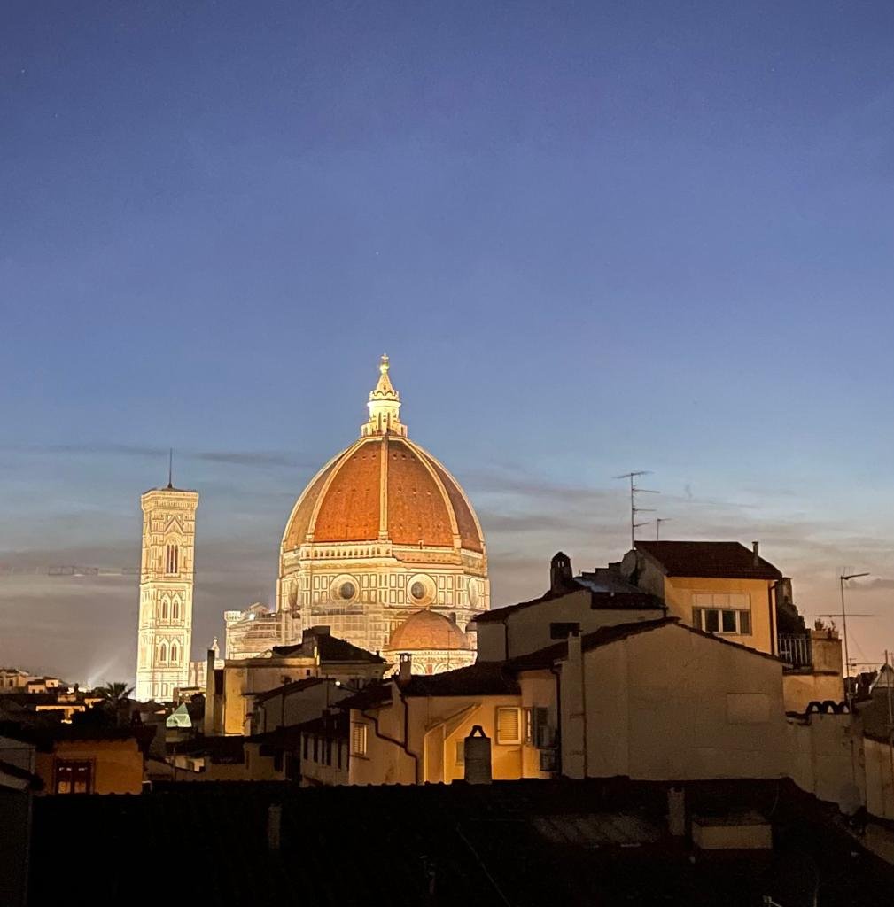 Brunelleschi's dome lit at twilight, seen across Florence rooftops