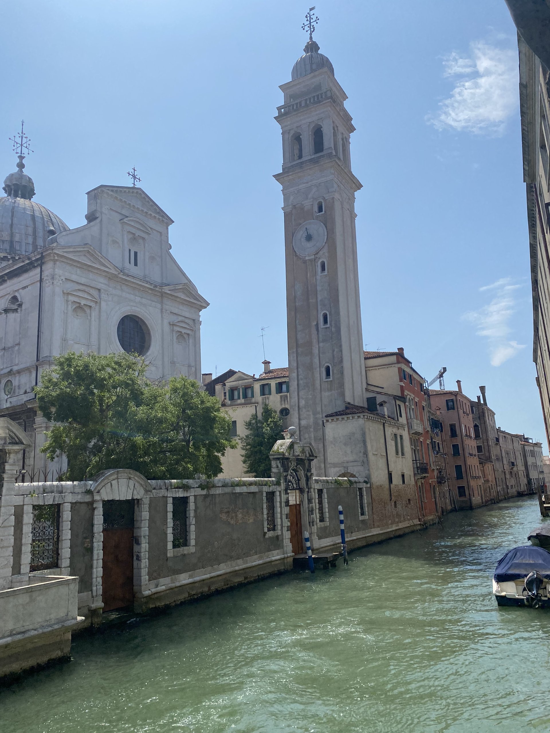 A quieter Venetian canal with a leaning bell tower in the distance